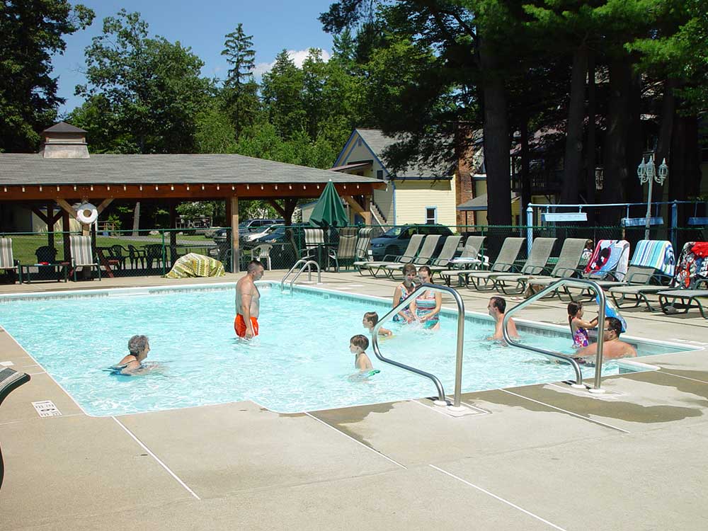 pool area with lounge chairs and swimmers